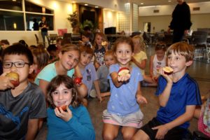 5 children sitting together holding apples