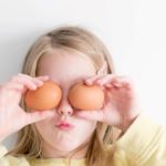 girl holding eggs over eyes